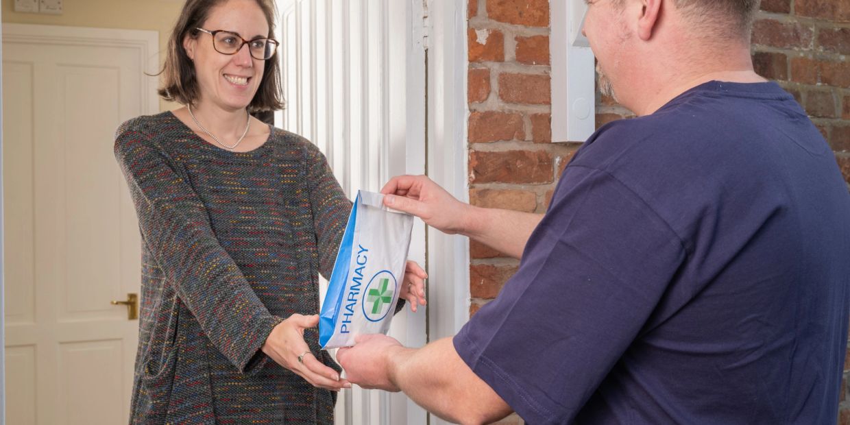 Woman receiving a pharmacy package at the door.