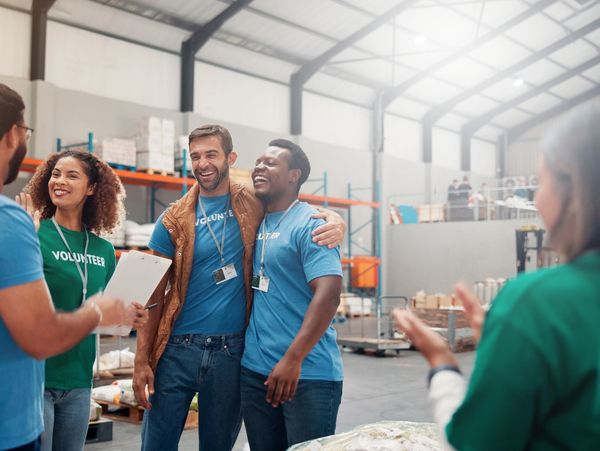 Volunteers smiling and celebrating teamwork in a warehouse setting.