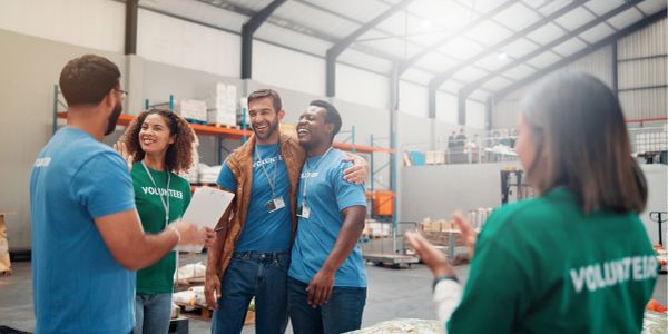 Volunteers laughing and socializing in a warehouse.