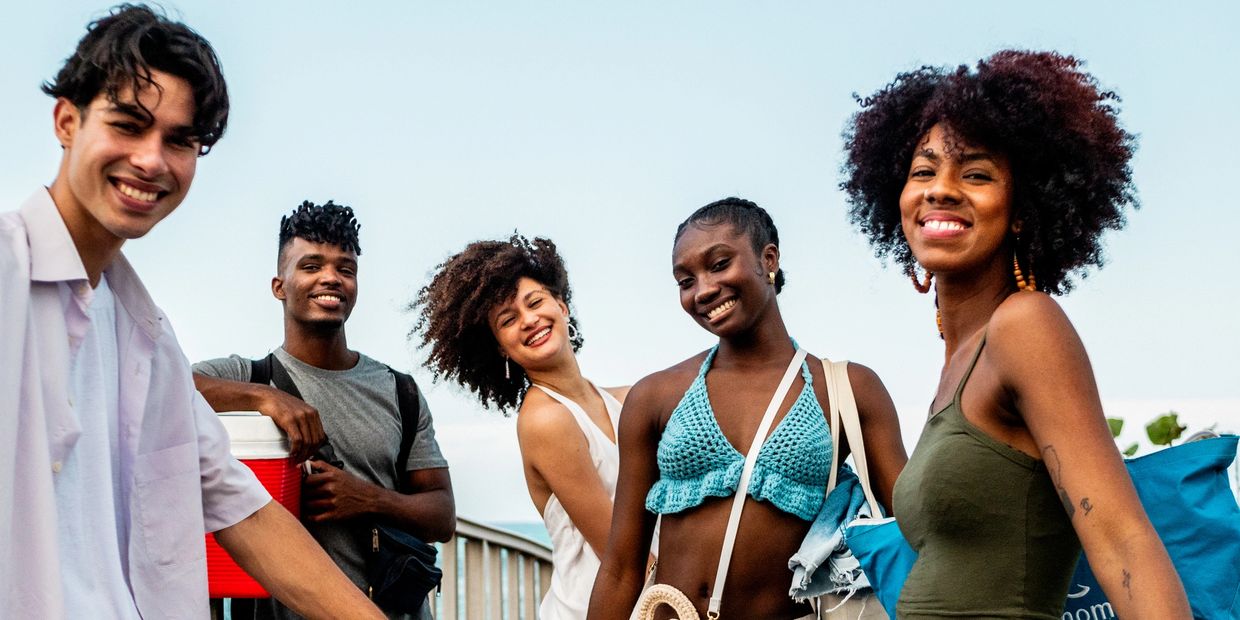 A group of five friends smiling outdoors on a sunny day.