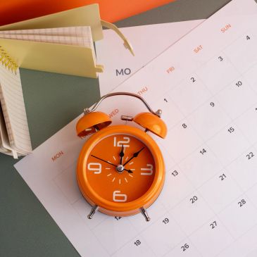 Orange alarm clock on a calendar page.