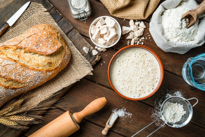 Ingredients for preparing homemade bread shot from above. Yeast, wheat flour, water and salt. High resolution 42Mp studio digital capture taken with SONY A7rII and Zeiss Batis 40mm F2.0 CF lens