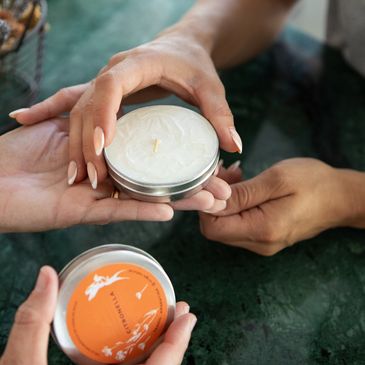 Two people holding a citronella candle in a tin container.