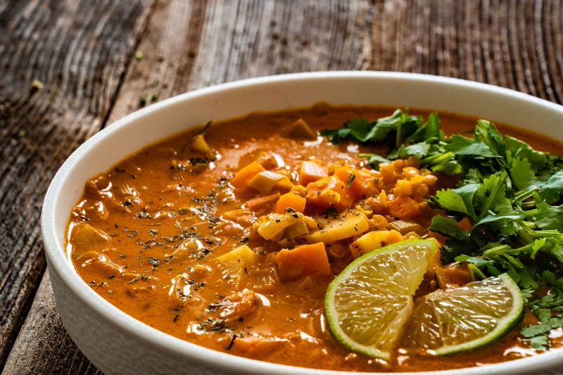 Red lentil sweet potato and coconut milk soup on wooden table
