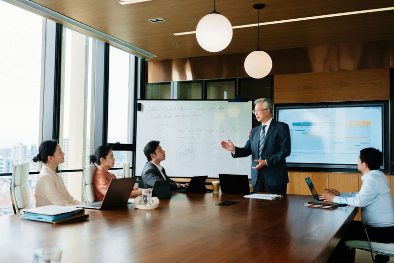 Asian senior businessman  having a meeting with her team in office boardroom. Group of business colleagues planning together in meeting.