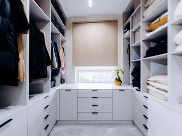 Spacious walk-in closet with built-in shelves, hanging rods, drawers, and organized storage 