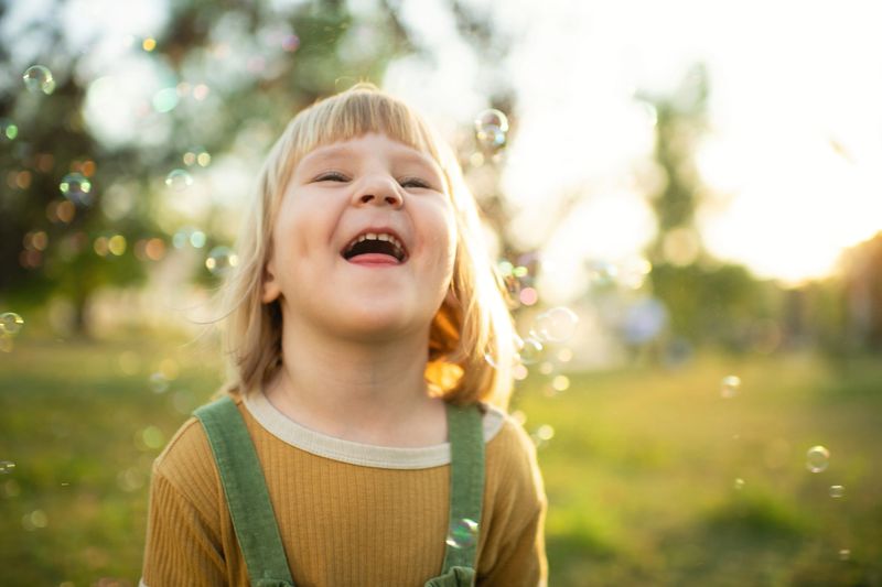Cheerful child laughing while playing in a sunny park during a photo session.