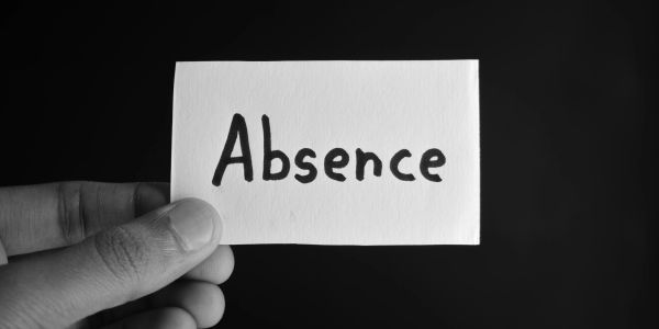 Hand holding a card with the word 'Absence' against a black background.