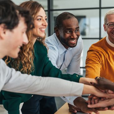 A diverse group of colleagues joining hands in teamwork and celebration.
