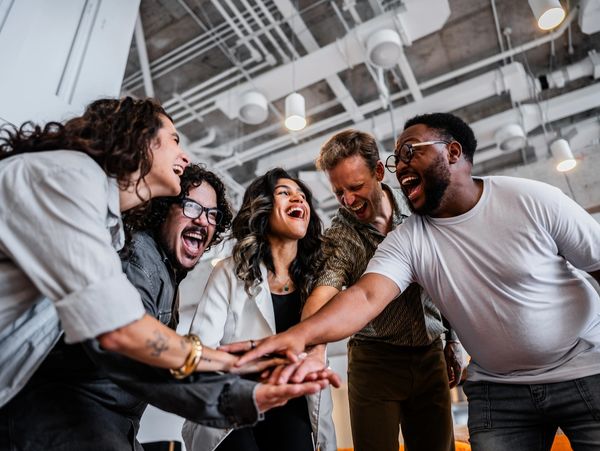 A joyful group of colleagues stacking hands in a team cheer.