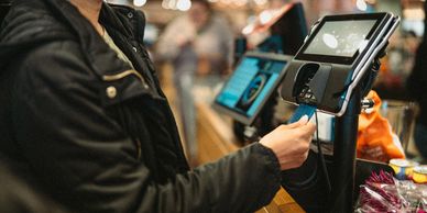 A person swiping a card at a payment terminal in a store.