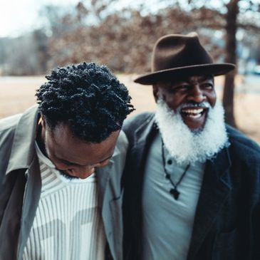 Two men laughing outdoors on a cool day.