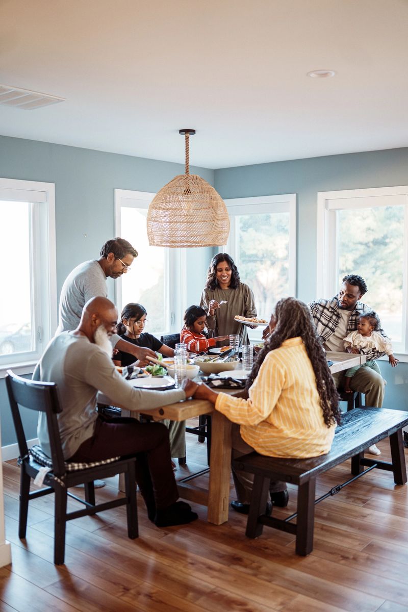 A multiracial multi-generation family gathers around a dining room table and enjoys a homemade meal for dinner while spending a fun and relaxing weekend vacation together.