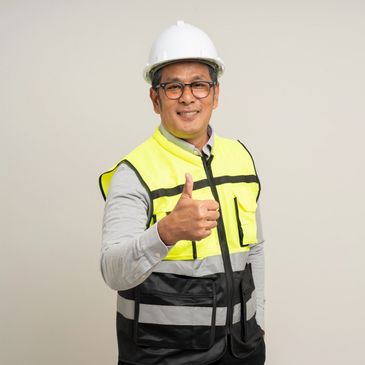 Smiling construction worker in safety gear giving thumbs up.