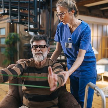 Elderly man doing resistance band exercise with nurse assistance.
