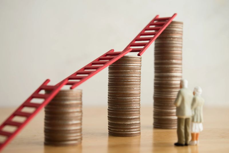 Love old senior couple looking at growth stack coins graph chart with red ladder. Financial planning for retirement, savings, pension, gain return on investment, wealth and so on concept.