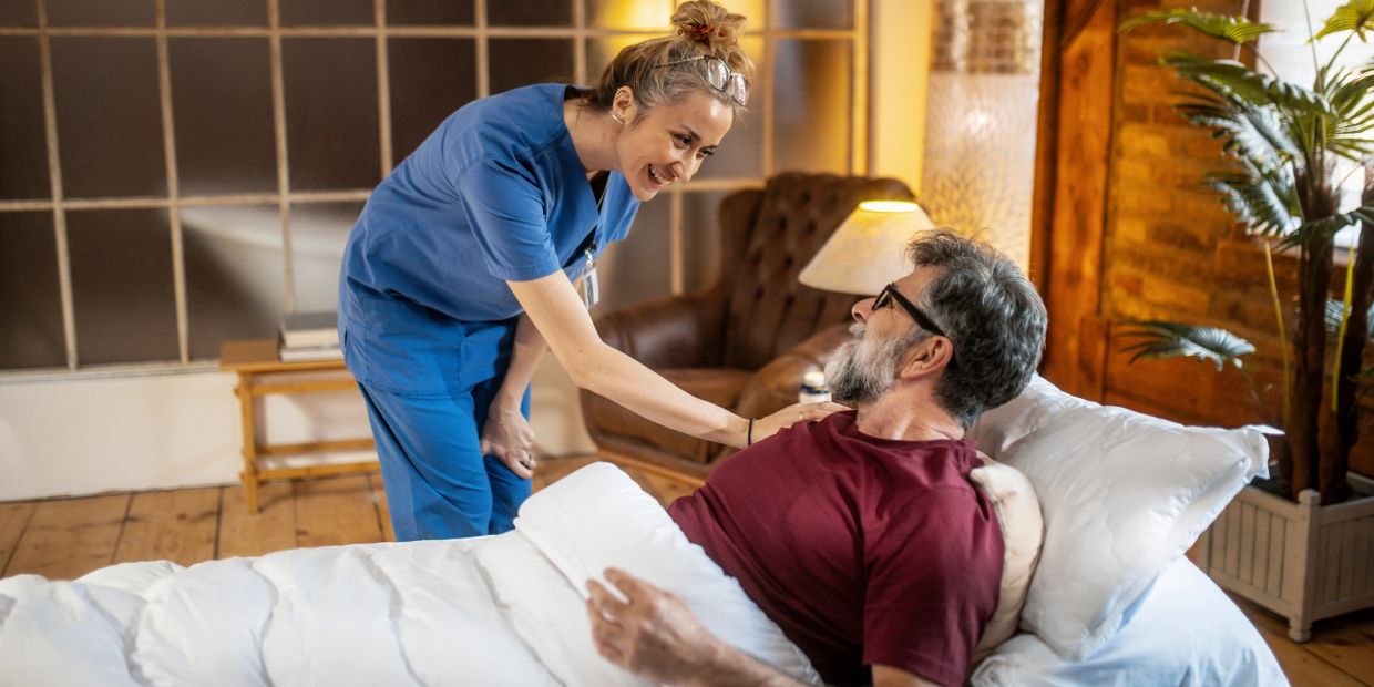 Nurse comforting elderly man in bed.