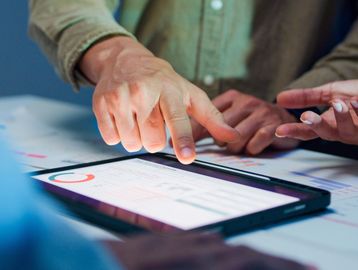 Hands pointing at a tablet screen during a collaborative work session.