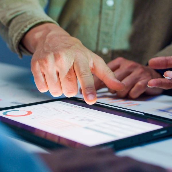 People discussing data displayed on a tablet during a meeting.