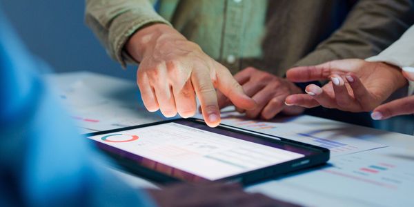 People discussing data displayed on a tablet during a meeting.