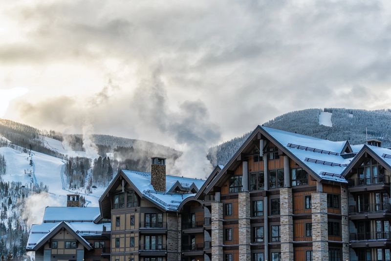 Vail, Colorado rocky mountains ski resort chimney smoke modern hotel buildings in cold winter snow season at sunrise