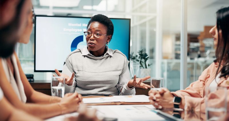 Office, people and businesswoman with discussion in meeting, employees wellness and health program. Boardroom, colleagues and hr manager with feedback in workshop, support policy and review report