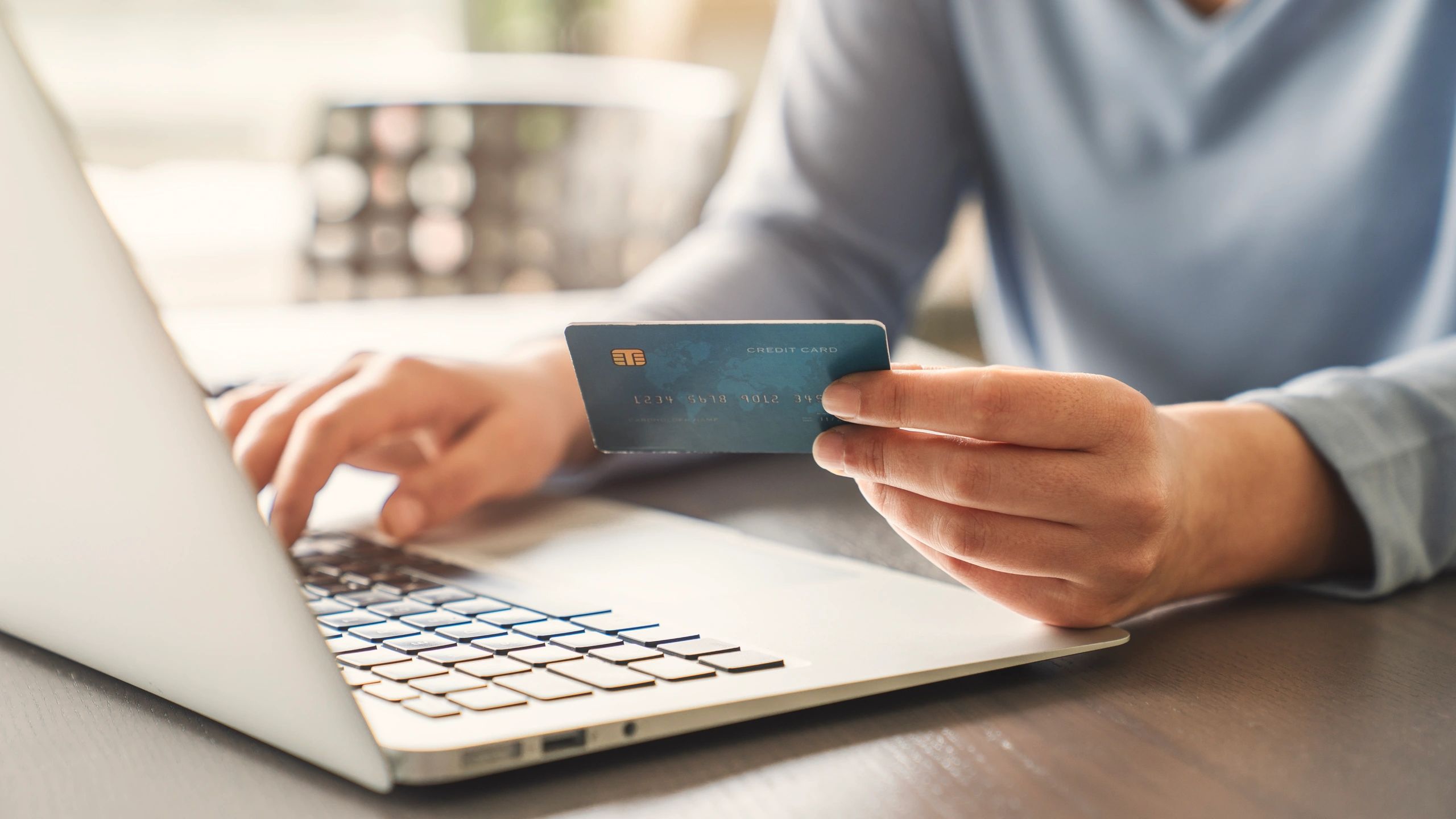 Person holding credit card using laptop.