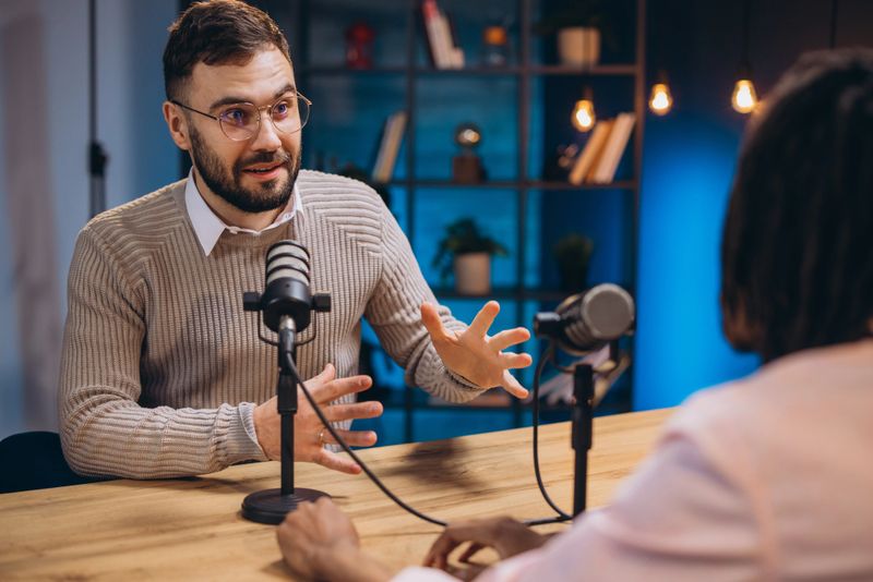 Professional podcast duo collaborating, speaking into microphones while recording engaging audio content in modern studio setting
