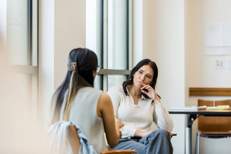 Serious discussion between two women during a therapy session.  Focus on mental wellbeing and emotional support.