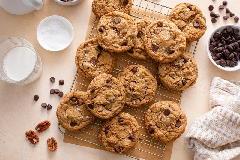 Chocolate chip cookies with pecan nuts, freshly baked cookies on a cooling rack served with milk