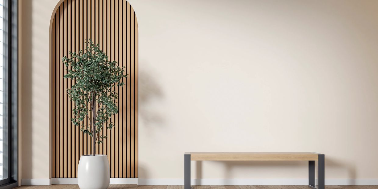 Minimalist interior with a potted plant and wooden bench against a beige wall.
