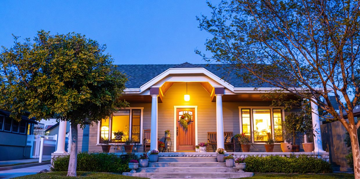 Cozy house with warm lights and a welcoming porch at dusk.