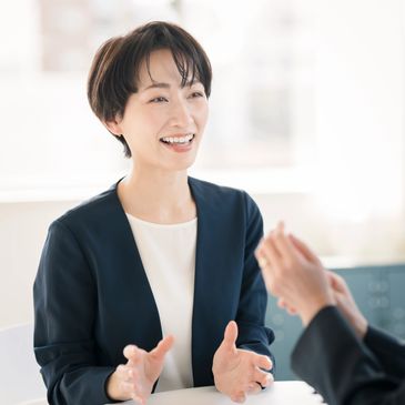 Smiling woman in a navy blazer engaged in a friendly conversation.