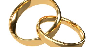 Two intertwined shiny gold wedding bands on white background.