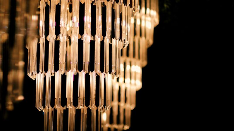 A refined interior scene featuring sparkling crystal chandeliers illuminating a beautifully decorated table. The combination of shimmering lighting and sophisticated decor elements creates a luxurious and inviting ambiance, ideal for weddings, fine dining, or upscale event settings. Perfect for themes related to interior design, elegance, and celebration.