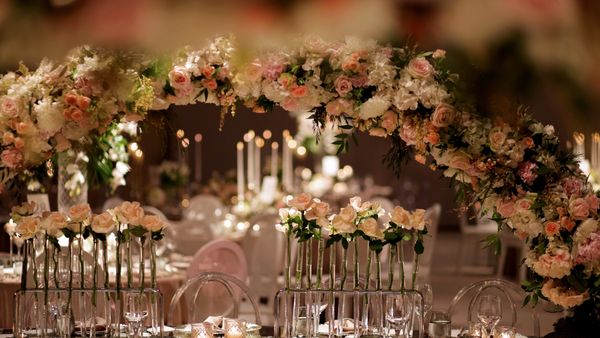 Elegant floral arch and rose centerpieces at a formal event table setting.