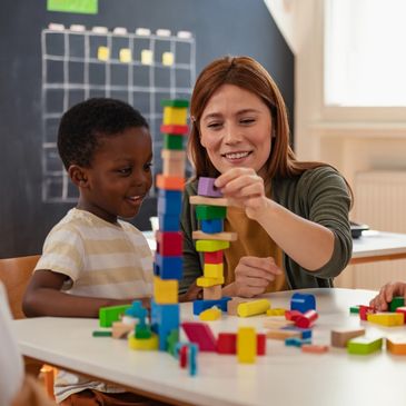 A teacher playing with building blocks with a child