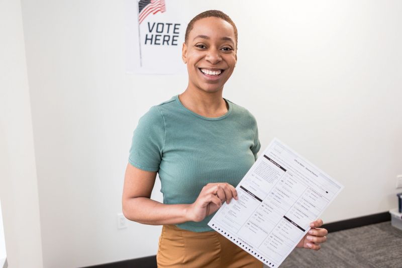 Happy woman smiling while holding her ballot. Voting, election, democracy.