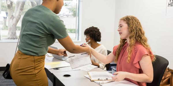 A woman submits a voting ballot to an election official at a polling station.