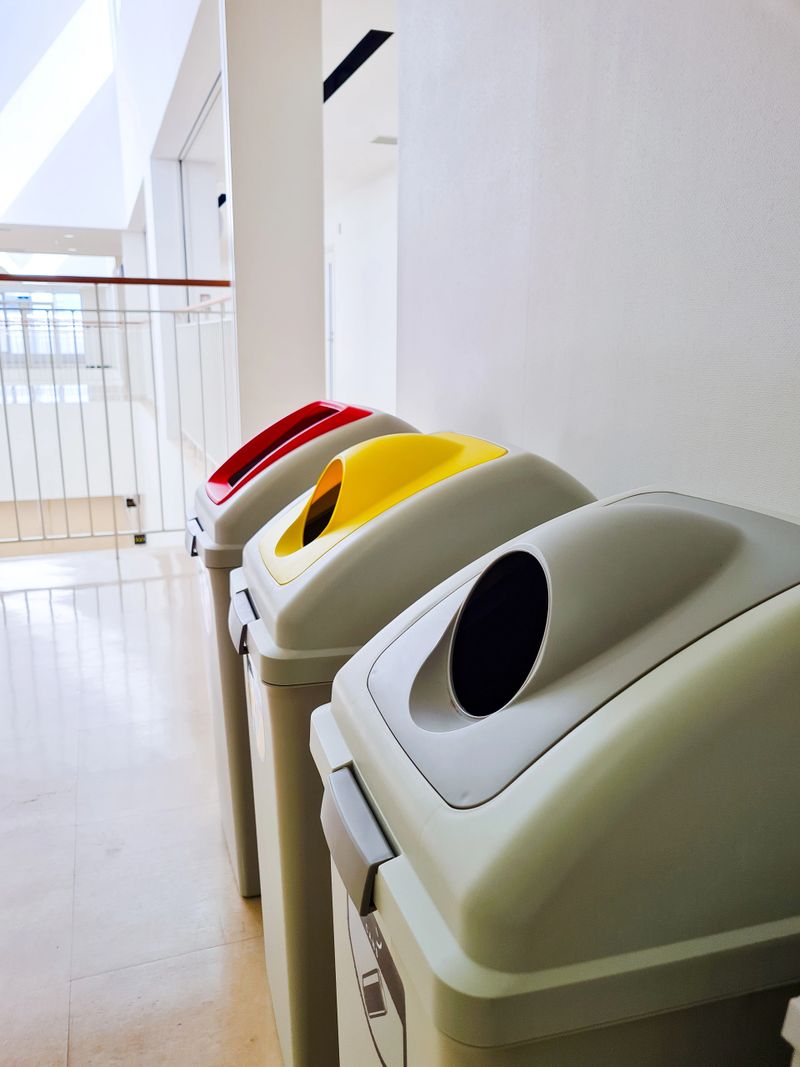 Side view of three trash bins with holes for throwing out waste, located in a clean and modern interior, symbolizing organization and care for the environment.
