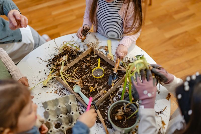 Children explore plant bulbs and soil during a hands-on gardening activity, promoting environmental education and sensory learning in a diverse classroom setting.