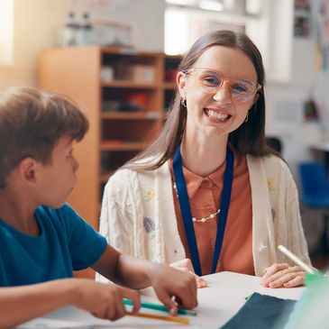 Smiling teacher engaging with students in a bright classroom.