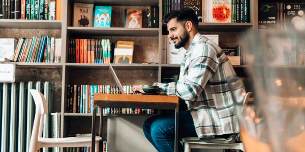 Man working on laptop in a bookstore.