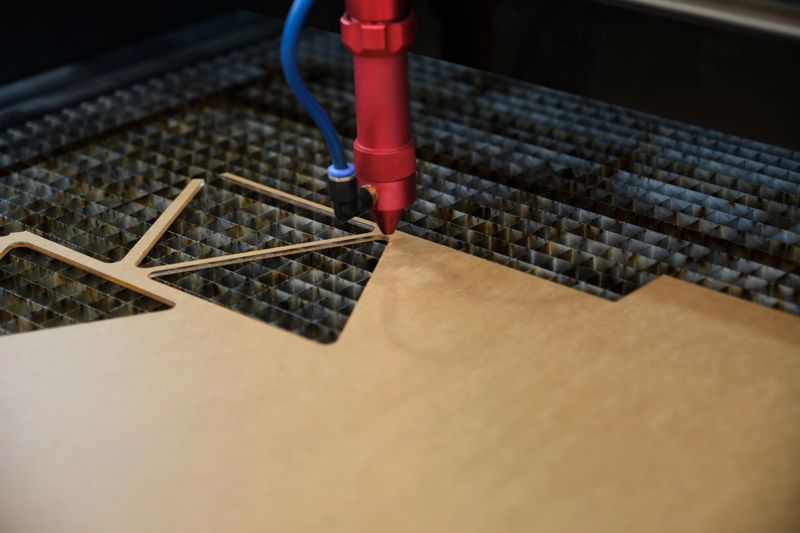 Close-up view of a laser cutting machine operating on a material, creating precise patterns for manufacturing or crafting purposes, showcasing advanced technology and industrial applications.