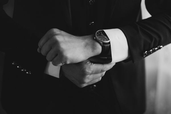 Man adjusting his wristwatch while dressed in a suit.