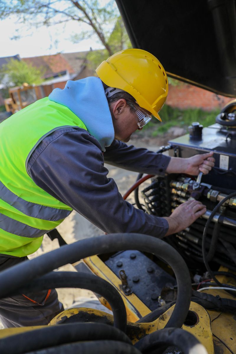 Senior technician repairing hydraulics on construction machinery