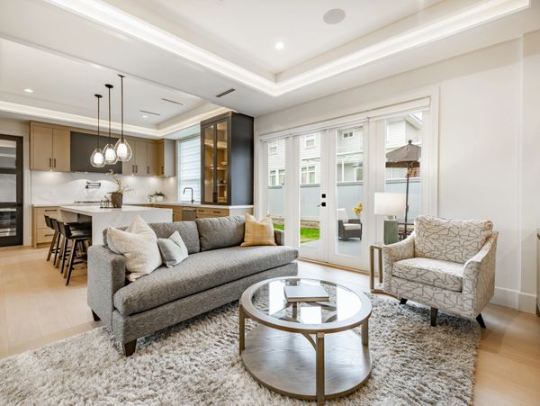 Bright open living room with modern kitchen and large windows.