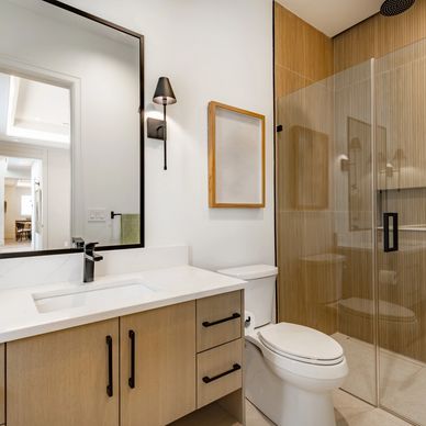 Modern bathroom with wooden accents and glass shower enclosure.