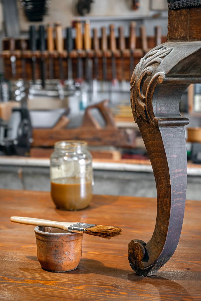 Restoration of an antique Elizabethan chair in a traditional furniture workshop with wax polish and a brush on the workbench.
