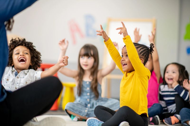 Group of diverse children seated on the carpet of a classroom, engaging in a fun interactive activity, fostering learning, cooperation, and enjoyment.